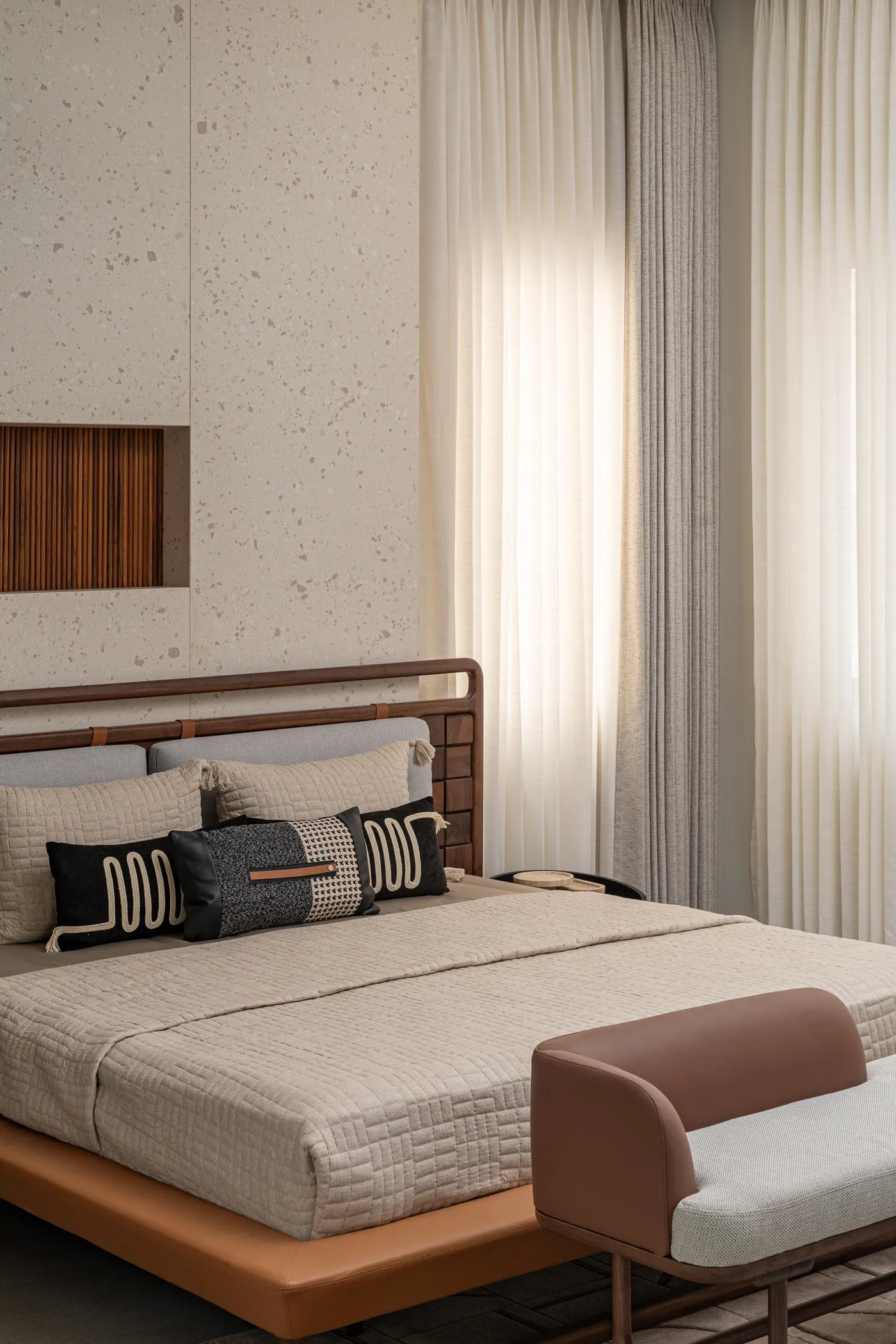 Bedroom with a timber-framed bed, layered cushions and sheer curtains